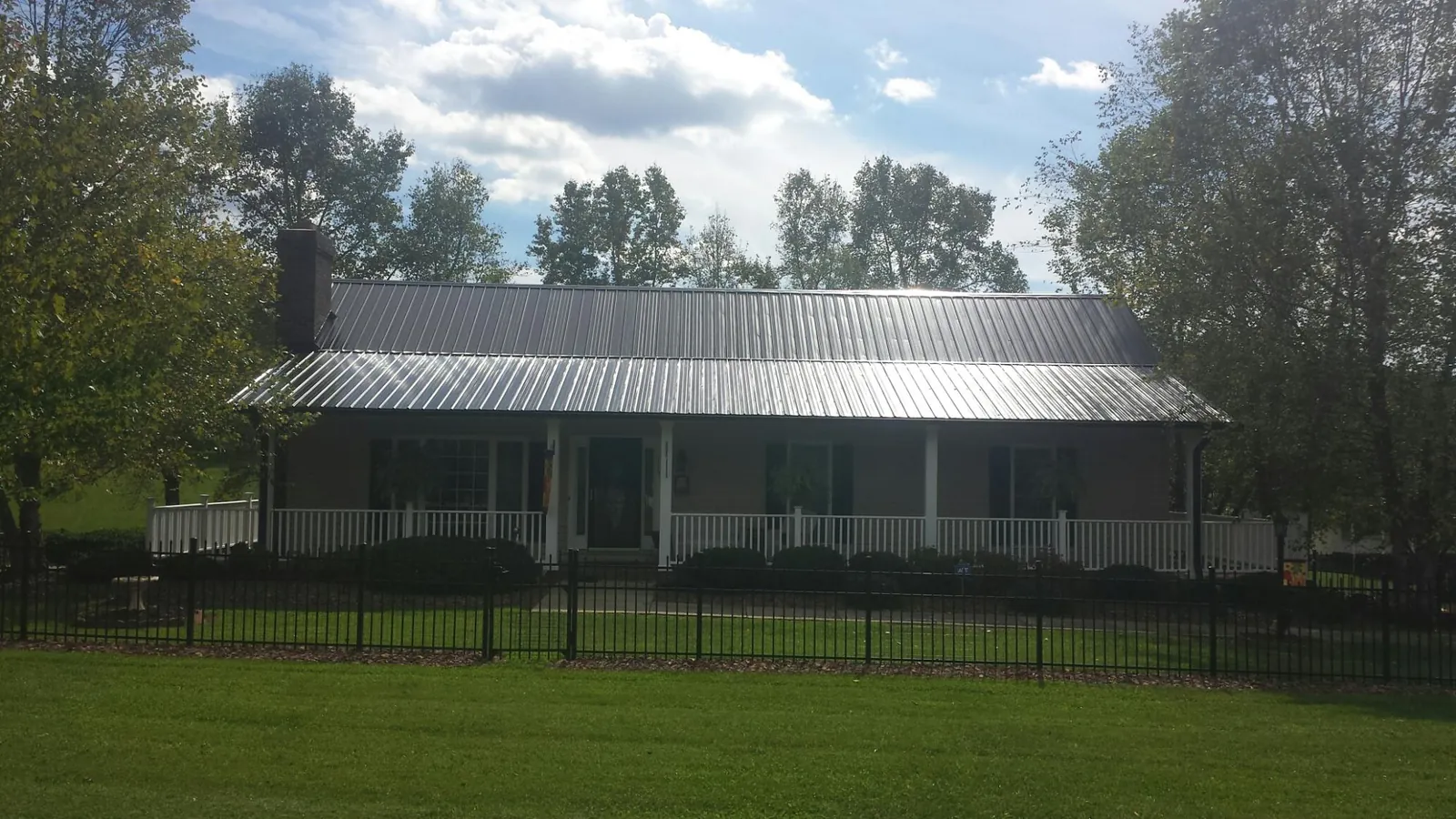 Gray metal roof on a brick ranch with a full width front porch — Gutter Guard Installation work by our crew in Ohio City